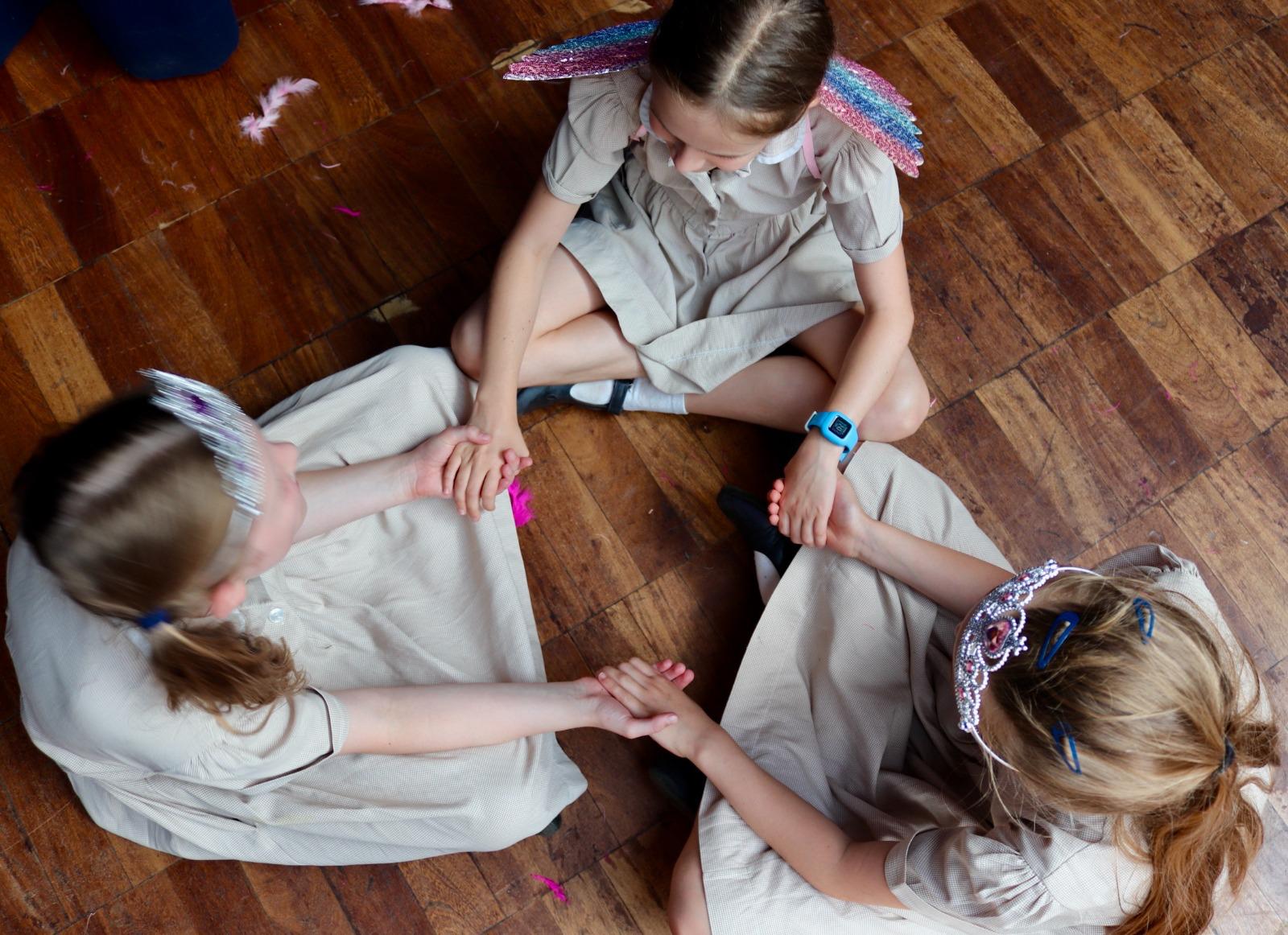 Three girls in fairy wings and tiaras playing a circle game