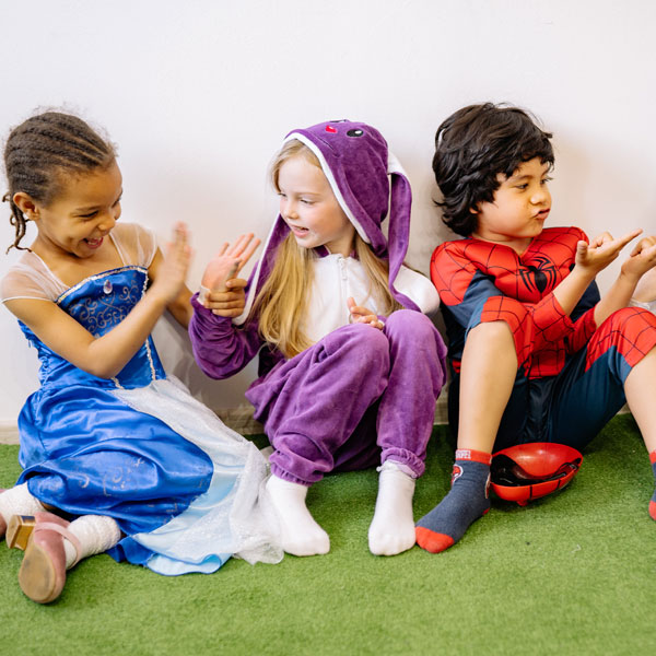 Three children dressed as a princess, a bunny and a superhero playing together